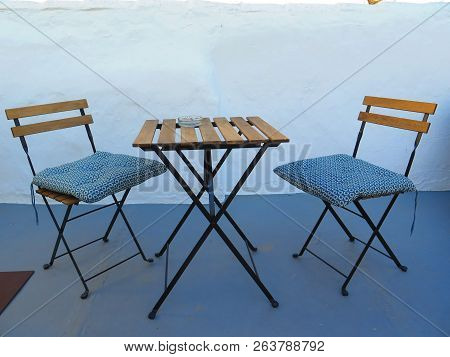 Two Spindly Chairs With Cushions And Small Square Table In Andalusian Courtyard Patio