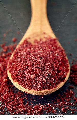 Close Up Of Ground Sumac Spice Powder In Wooden Spoon