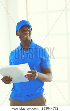 Portrait Of An Handsome Happy Deliverer With Folder