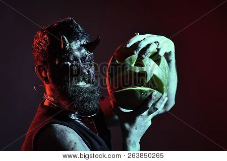 Halloween Darkness And Light Concept. Devil Show Teeth With Jack O Lantern. Man Demon Hold Pumpkin O