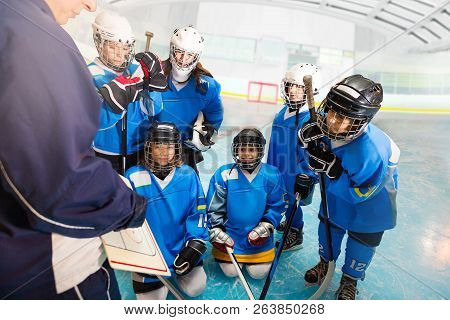 Coach Talking To Childrens Hockey Team On Rink