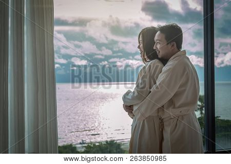 Asian Lovers In Bathrobe Suit Hugging And Sightseeing The Sea Beach When Waking Up From The Bed In L