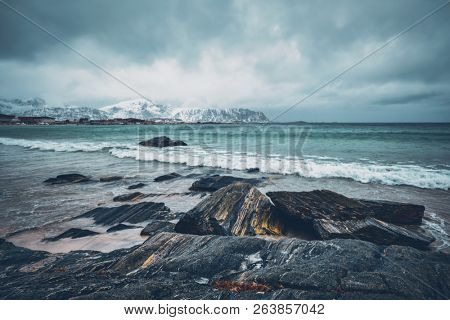 Waves of Norwegian sea on rocky beach of fjord. Ramberg beach, Lofoten islands, Norway