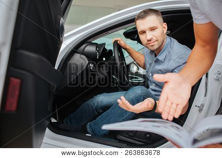 Picture Of Customer Sitting In White Car And Look Down. He Stratches His Hand. Manager Does The Same