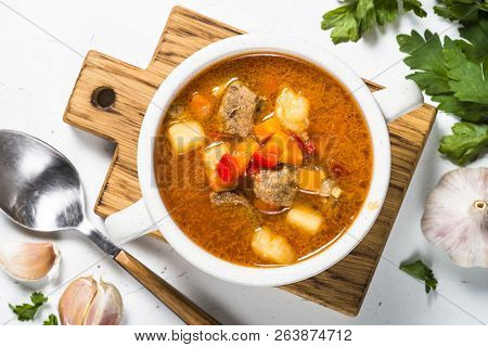 Goulash Soup With Meat And Vegetables On White Stone Table. European Cuisine. Top View With Copy Spa