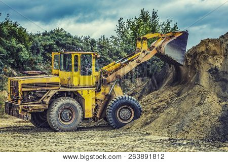 Wheel Loader Excavator With Backhoe Unloading Sand At Eathmoving Works In Construction Site Quarry
