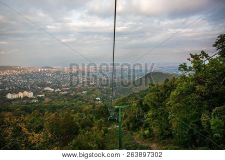 A Cabin Of Cableway Above The Autumn Forest, City Budapest In The Background