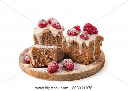 Chocolate Cake Decorated By White Glaze And Fresh Berries Of Raspberry Is Strewed With Icing Sugar L