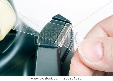 Macro Of A Male Hand Pulling Of Some Tape Of A Sellotape Holder