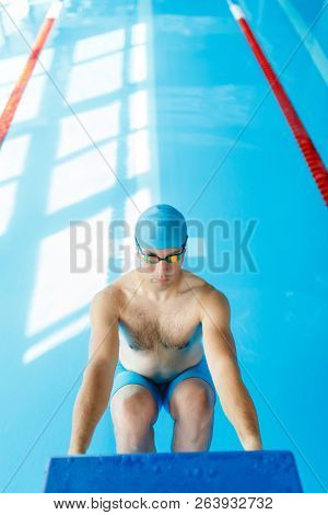 Image of young swimmer man in blue cap at side in swimming pool
