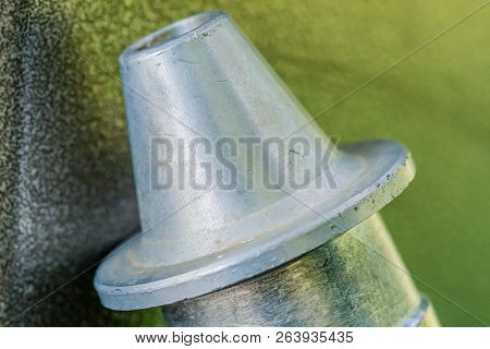 Closeup Of Triangle Shaped Flanged Metal  Nozzle Of Air Hose On Blurred Grayish Green Background.