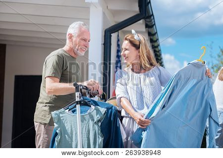 Loving Mature Couple Looking At Clothes While Visiting Weekend Yard Sale