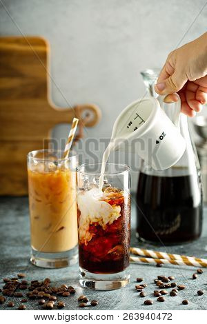 Refreshing Cold Brew Iced Coffee In Tall Glasses With Milk Or Creamer Pouring Over