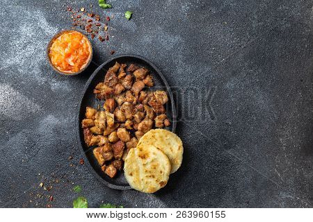 Colombian Food. Fried Pork Chicharron, Arepas And Colombian Tomato Sauce. Top View. Black Background
