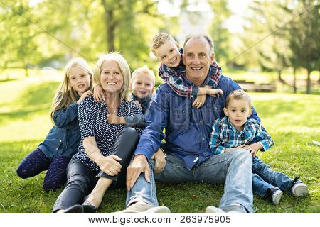 A Senior Person With Littleson On The Grass