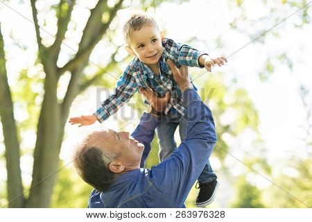 Grandfather And Littleson Having Fun In The Park