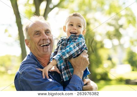 Grandfather And Littleson Having Fun In The Park