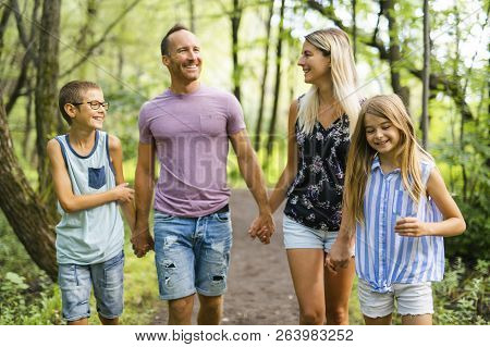 Happy Young Family In Forest Having Fun Together