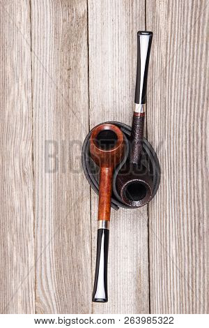 Top View Of Two Different Smoking Tobacco Pipes On Leather Stand On Wooden Background With Copy Spac