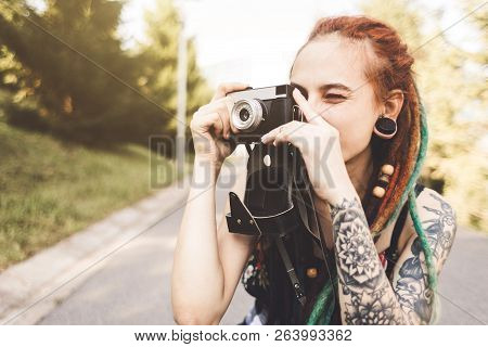 Young Girl With Tattoos And Dreadlocks Photographs Vintage Camera In The Park
