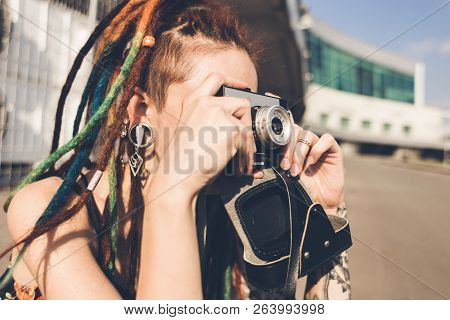 Young Girl With Tattoo And Dreadlocks Takes Pictures On Urban Industrial Background