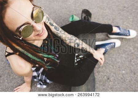 Young Girl With Tattoo And Dreadlocks Sitting In The Park