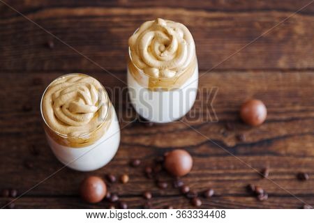 Top View Of Two Beautiful Glasses With Dalgon On A Wooden Table Surrounded By Chocolates And Coffee 