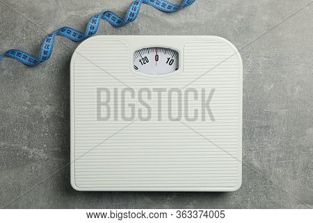 Scales And Measuring Tape On Gray Background. Weight Loss Concept
