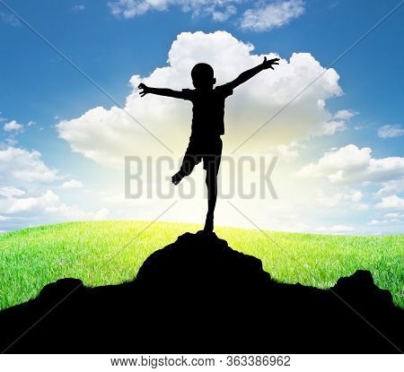 Happy silhouette of boy enjoy the nature. Spread arms to the sun and deep sky. Emotional and coceptual scene.