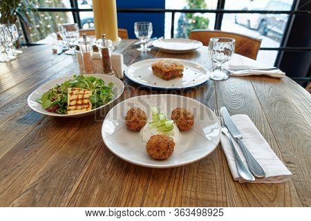 Set of three Greek dishes - fried Saganaki cheese, moussaka and zucchini fritters on restaurant table