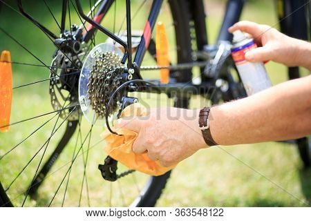 Senior Man Hands Cleaning The Bike By Spray And Rag, Doing Maintenance Of His Bicycle