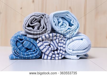 Clothes Stack For Newborn Boy. Close Up Of Rolled Up Kids Chlothes On White Chest Of Drawers In Fron
