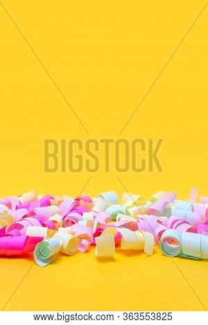 Paper Confetti For Baby Shower Party On Vibrant Yellow Background. Vertical Format. Copy Space. Pink