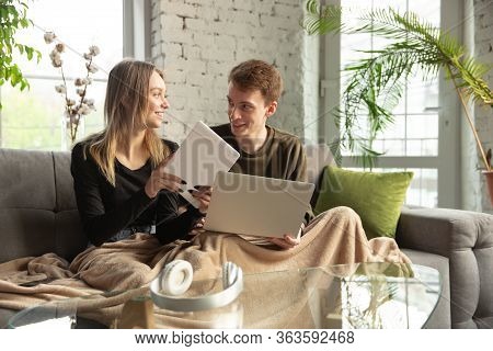 Attractive Young Couple Using Devices Together, Tablet, Laptop, Smartphone, Headphones Wireless. Com