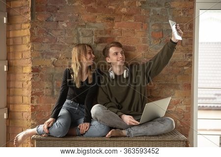 Attractive Young Couple Using Devices Together, Tablet, Laptop, Smartphone, Headphones Wireless. Com