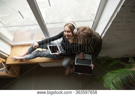 Attractive Young Couple Using Devices Together, Tablet, Laptop, Smartphone, Headphones Wireless. Com