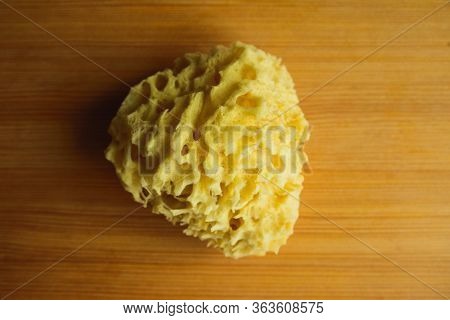 Top View Of Natural Sea Bath Cleaning Yellow Sponge For Washing On Wooden Table Background, Close-up