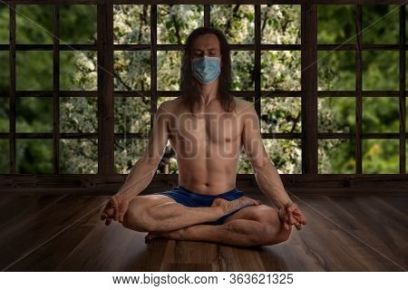 A Man Is Meditating At Home In A Mask. Stay At Home Until The Coronovirus Passes. Homemade Corontin.