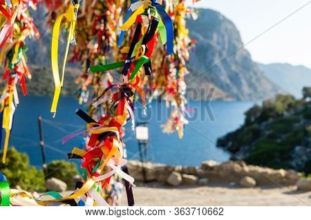 Tree In Festive Colored Ribbons On The Background Of The Sea And Mountains.
