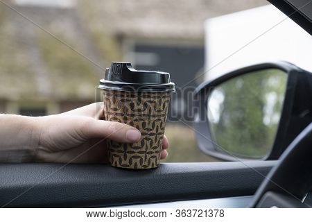 Woman's Hand With A Cup Of Coffee, Tea In Her Car With The Window Open. Safe During The Intiligent L