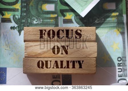 Focus On Quality Words On Wooden Blocks Put On 100 Euro Banknotes. Product Or Service Quality Concep
