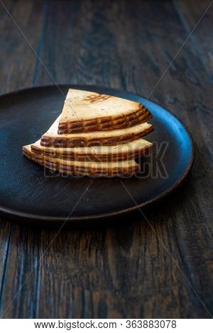 Spicy Circassian Triangle Smoked Cheese Slices On Dark Wooden Plate With Spices.