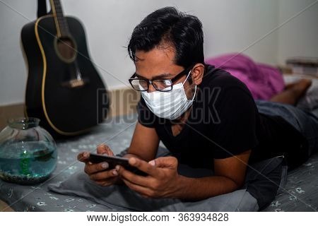 Portrait Of A Young Man Playing Mobile Video Games At Night Deu To Coronavirus Epidemic.