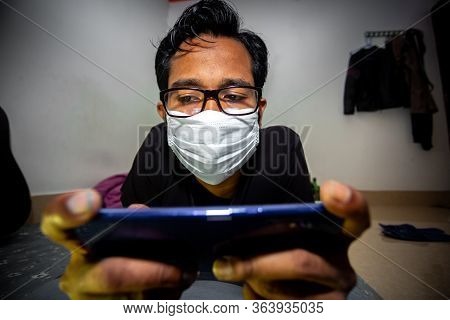Portrait Of A Young Man Playing Mobile Video Games At Night Deu To Coronavirus Epidemic.