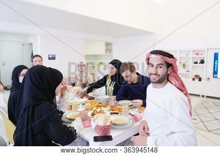 young arabian man having Iftar dinner with muslim family Eating traditional food during Ramadan feasting month at home. The Islamic Halal Eating and Drinking Islamic family