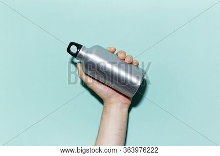 Close-up Of Male Hand Holding Reusable, Aluminum Thermo Bottle For Water, On Studio Background Of Cy
