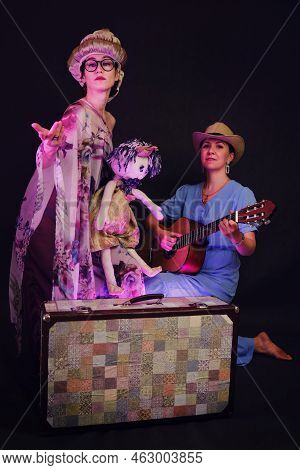 Happy Women In Funny Wigs Give A Musical Performance On A Studio Black Background. Smiling Women Sho
