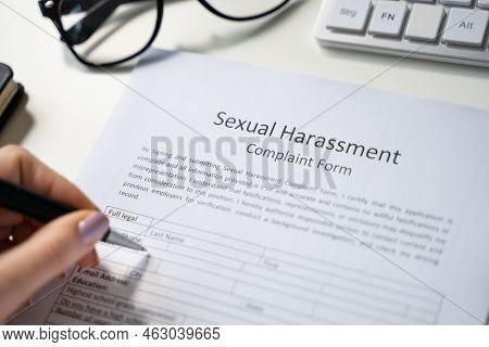 Close-up Of A Human Hand Filling Sexual Harassment Complaint Form With Pen