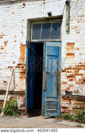 Weathered Timeworn Shabby Wooden Door Entrance To Old Brick Building.