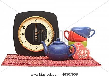 Set van kleurrijke kopjes met oude muurklok op wit. Tea time